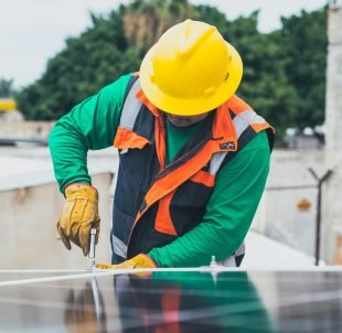 Professional solar panel technician working outdoors with PPE.