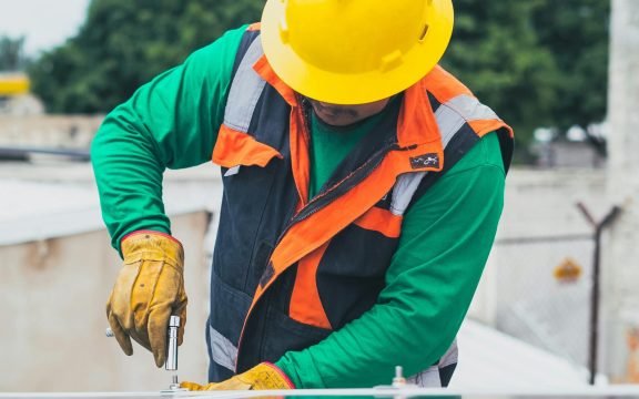 Professional solar panel technician working outdoors with PPE.