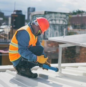 Technician in safety gear installing solar panels on a rooftop, ensuring energy efficiency.